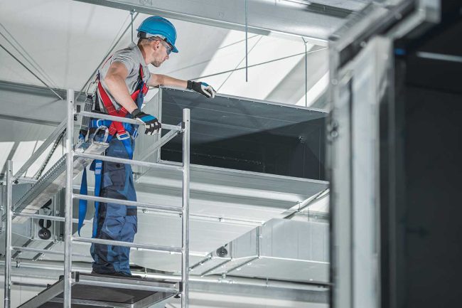 Trabajador inspecciona área previo a una limpieza de ductos de aire acondicionado.
