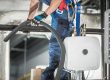 Trabajador realiza mantenimiento aire acondicionado industrial.