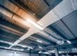 Sistema de distribución de aire por ductos en el techo de un almacén amplio.