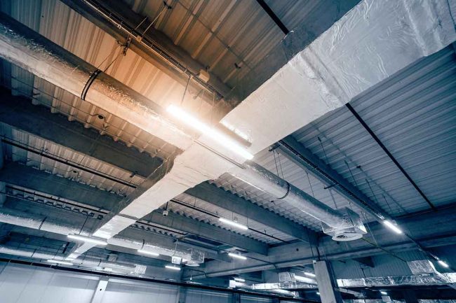 Sistema de distribución de aire por ductos​ en el techo de un almacén amplio.